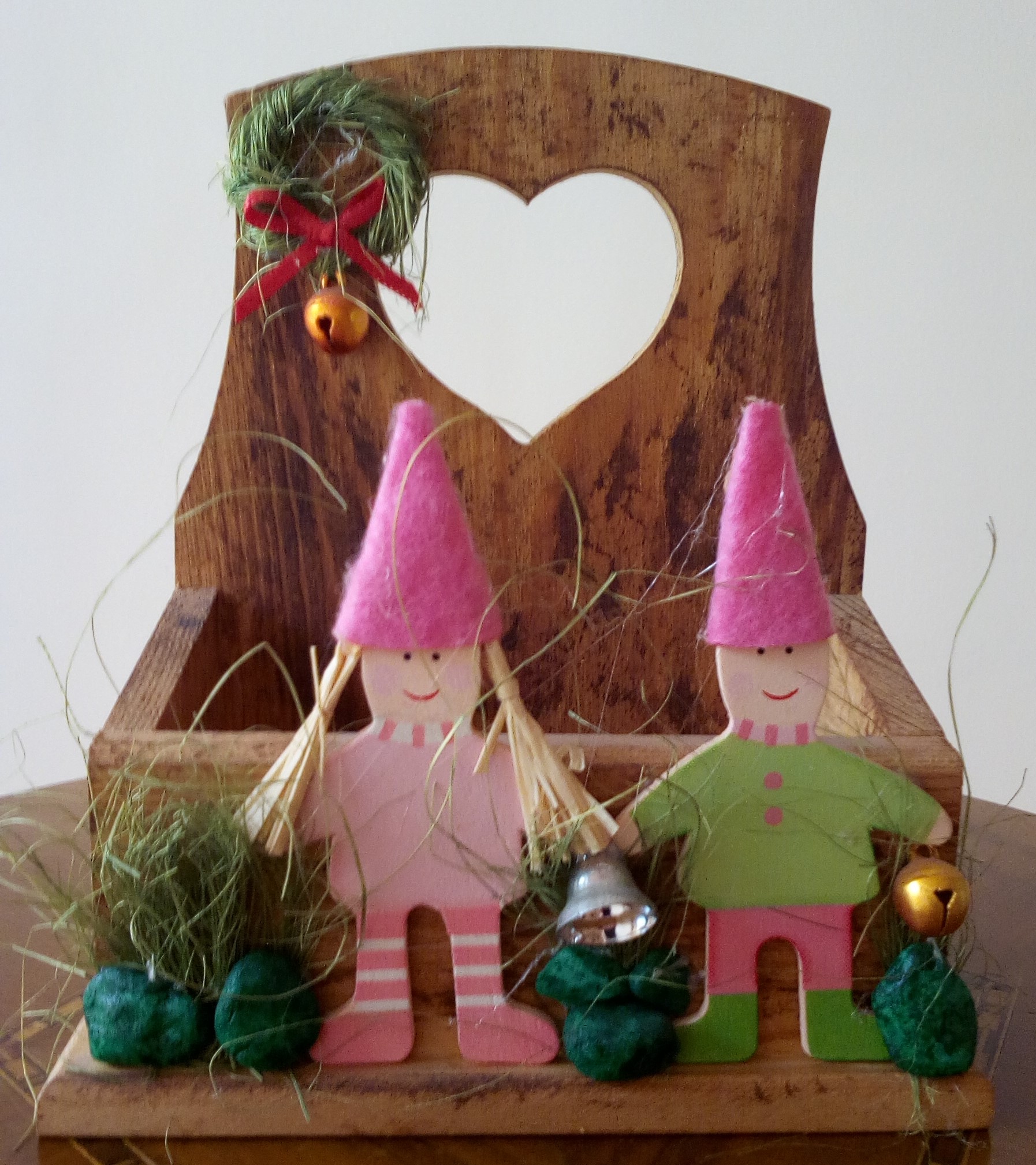 Cosa Nostra-Kids of Christmas. Ξύλινη θήκη με ξύλινες φιγούρες παιδάκια σε ροζ-πράσινο χρώματα και χειροποίητη διακόσμηση από φυτικά, μεταλλικά κι υφασμάτινα στοιχεία και χαλίκι. Μπορεί να χρησιμοποιηθεί ως επιτραπέζιο ή ως επιτοίχιο διακοσμητικό. Συνολικό μέγεθος: ύψος 13cm x μήκος 11.5cm x πλάτος 6cm. Ωφέλιμο θήκης: ύψος 3cm x μήκος 9cm x πλάτος 4cm.