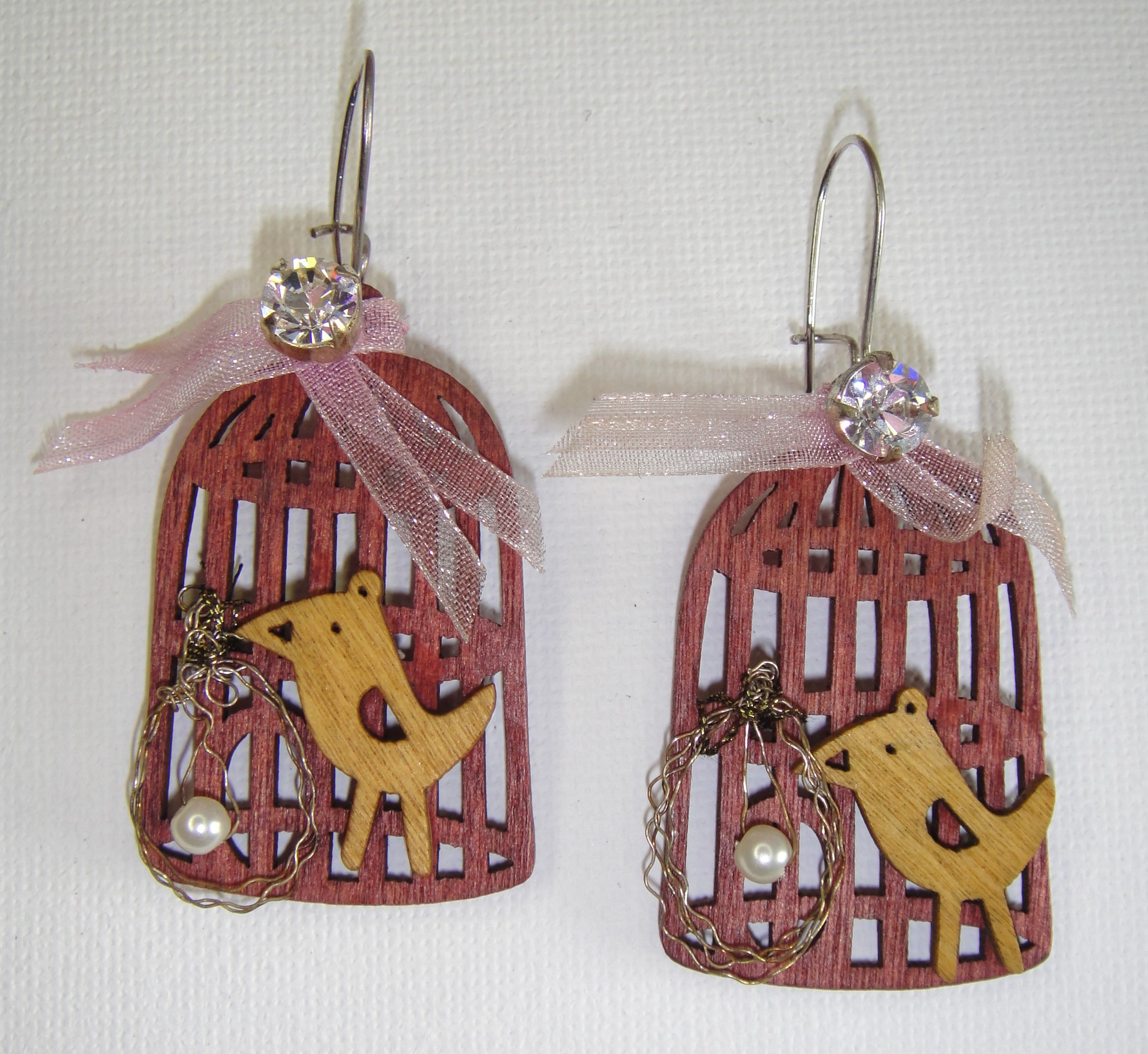 Cosa Nostra Handmade Earrings CAGE-SWAROVSKI. Χειροποίητα σκουλαρίκια σε νίκελ βάση και ξύλινη βάση-κλουβάκι με πουλάκι, Swarovski, οργάντζα, σύρμα, συνθετική πέρλα. Μάκρος συνολικό: 6cm/Στοιχείο: 3.5cm x 2.7cm.