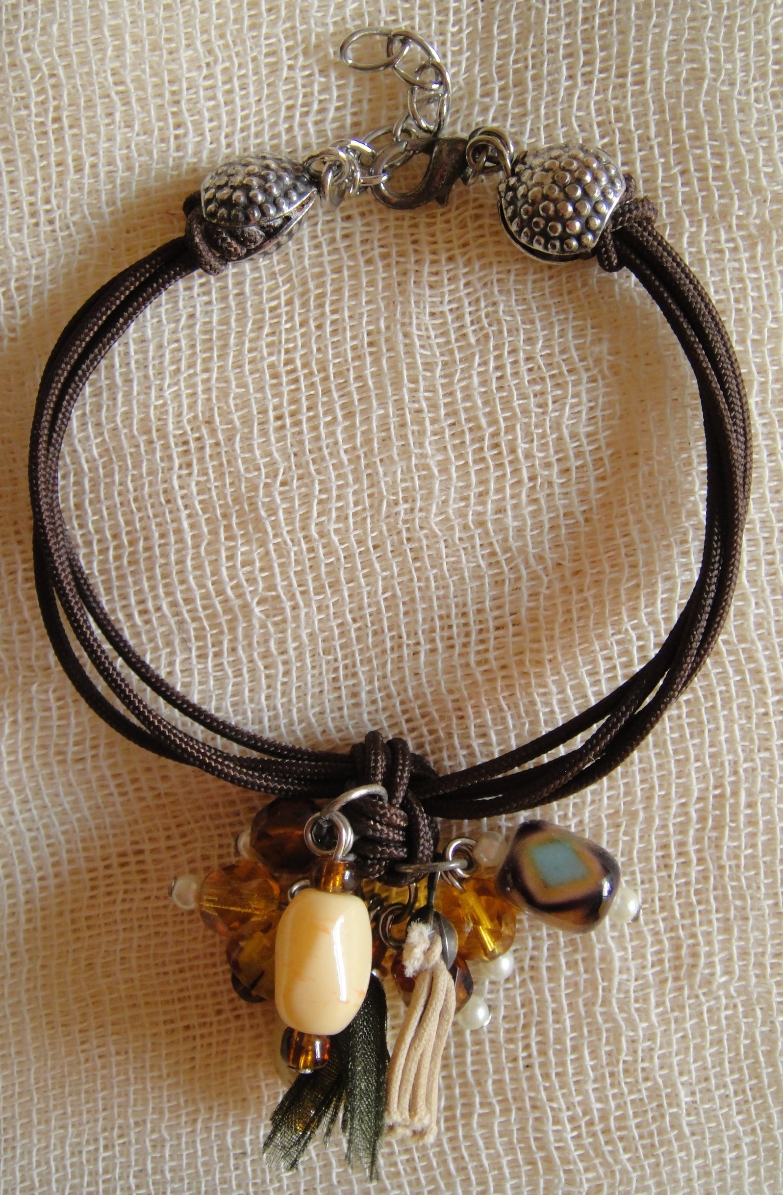 Cosa nostra handmade bracelet brown beads bouquet. Χειροποίητο βραχιόλι με κορδόνι, νίκελ αλυσίδα και κούμπωμα, μεταλλικά στοιχεία, στρας, χάντρες (γυάλινες, απλές), φουντάκι από δερματίνη κι οργάντζα. Μήκος ≈22cm.